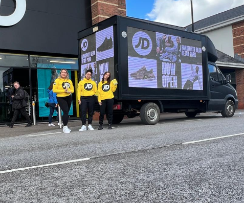 Digital advertising van displaying vibrant, high-resolution LED screen ads on the side panel, parked in an urban setting. The mobile billboard shows a dynamic, eye-catching advertisement, ideal for reaching audiences in high-traffic areas